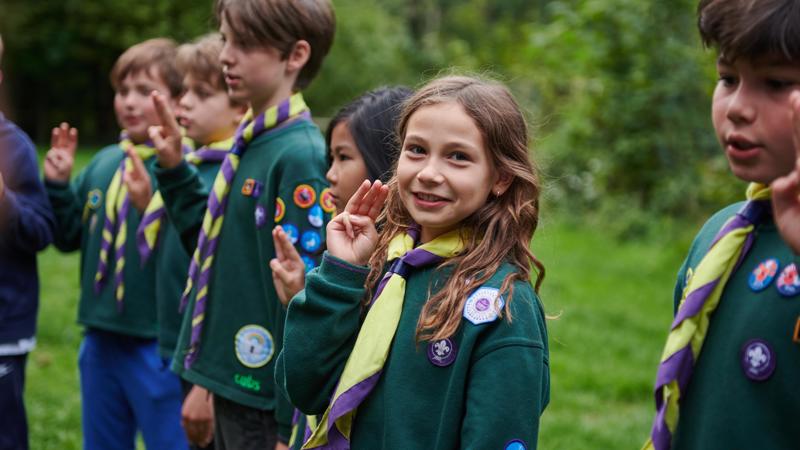 The front image of a Cub Scout making her promise before joining.